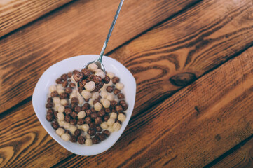 Cornflakes in a plate on a wooden background.
