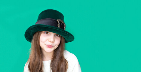 A closeup portrait of preteen girl in St. Patrick's Day hat on green backgroundwhite. Copy space