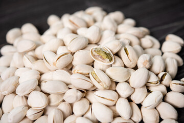 Pile of pistachios in the peel close-up on a wooden table. Selective focus