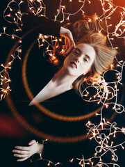 A young girl with sparkles on her cheeks. Christmas lights glow around. Magical mood