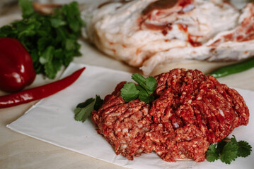Red fresh minced meat on the background of lamb legs, red pepper and greens