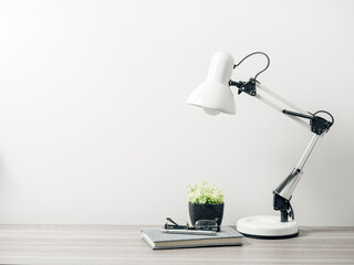 Workspace with notebook, tree pot and table lamp with living room white wall