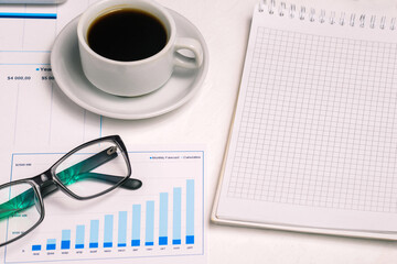 Worker office desk with coffee cup, notepad and diagram. Accounting and finance. Company profit growth concept.