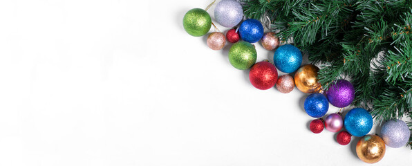 Multicolored Christmas balls of different sizes and artificial tree branches on white. Festive background with copy space