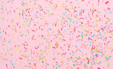 Tuinposter rainbow sprinkles on pink background © Alex
