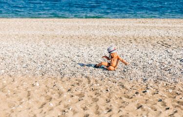 Fototapeta na wymiar Lonely toddler girl sitting on beach