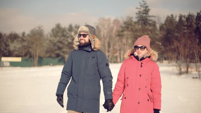 Couple Walking And Enjoying Winter.Freezing Day On Holiday Vacation Trip.Happy Loving Family Traveling On Snowy Park.Woman And Man Holding Hands Walking In Parka.Relax Lifestyle Having Fun In Cold Day