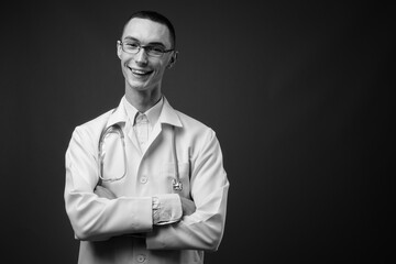 Young handsome androgynous man doctor against gray background