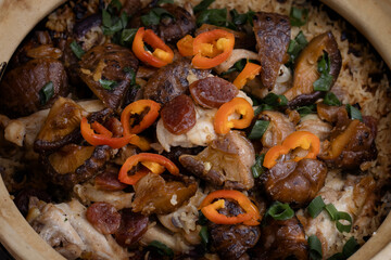 Chicken rice cooked in a clay pot. Garnished with spring onion and red chili pepper.