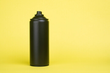 Black aerosol can on a yellow background.