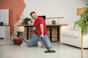 Young man having fun while vacuuming at home