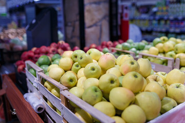 Soft focused shot of fruit department in grocery store, supermarket, mall, hypermarket or shopping center. Red, yellow and green apples in boxes. Healthy eating, avitaminosis  concept.