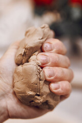 Obraz premium Hand squeezes a piece of clay. Woman preparing clay to make pottery at table in workshop. Handmade Design Art