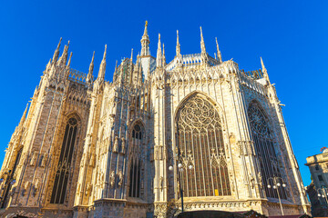 Naklejka premium Famous church Milan Cathedral Duomo di Milano with Gothic spires and white marble statues. Top tourist attraction on piazza in Milan Lombardia Italy. Wide angle view of old Gothic architecture and art