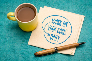 work on your goals daily - motivational reminder, handwriting on a napkin with a cup of coffee,...