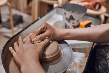 Women working on potters wheel making clay objects in pottery workshop