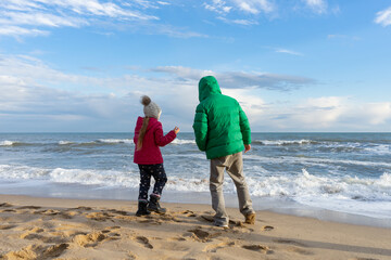 Children play on the seashore. The water surface is covered with waves