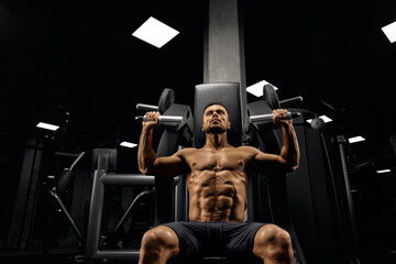 Shirtless caucasian bodybuilder training back on simulator.