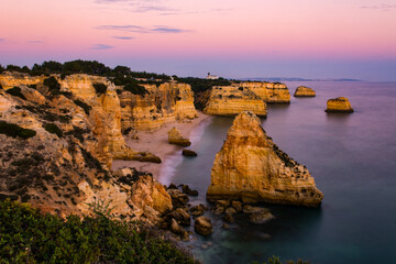 Scenic sunset view of Praia (English Beach) da Marinha and the nearby cliffs and the Atlantic Ocean near Lagos in the Algarve in Portugal. Soft focus, long exposure, low light