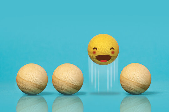 Wooden balls like emoticons. Concept of happiness. Blue background
