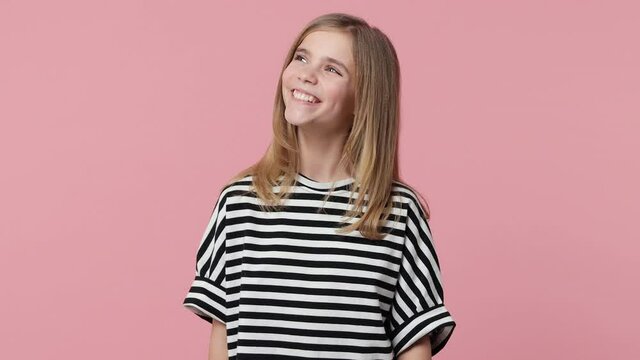 Smiling laughing little blonde kid girl 12-13 years old wearing white black striped casual t-shirt isolated on pastel pink color wall background studio. Childhood lifestyle concept. Looking aside up