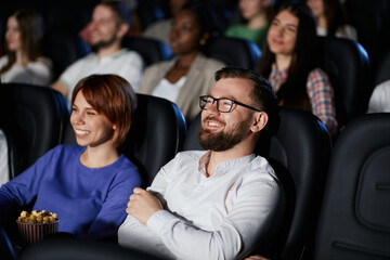 Emotional couple watching comedy in movie theater.