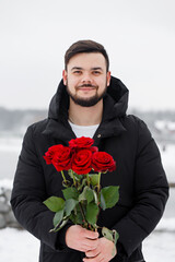 romantic young man with bouquet of red roses in hands