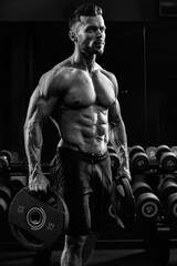 Fototapeta na wymiar Tensed male bodybuilder holding weights.