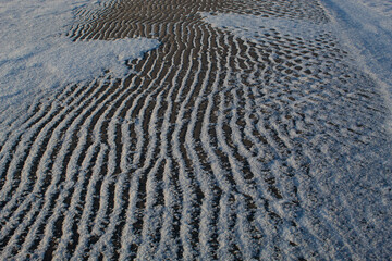 snow and sand on the beach at winter