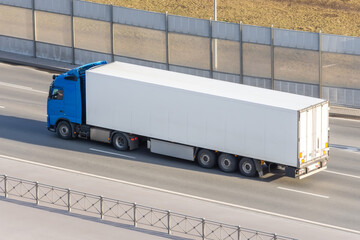 White truck with gray awning trailer rides on a city highway, side aerial view. © aapsky