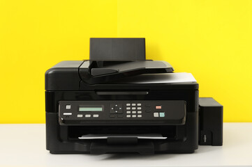 New modern printer on white table against yellow background