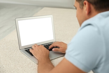 Fototapeta na wymiar Man using laptop for search on floor indoors, closeup