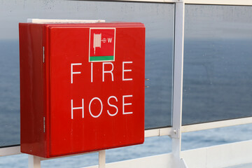 Fire Hose,  rote vier eckige box mit Feuerwehrschlauch an der Reling von grossem Kreuzfahrtschiff
