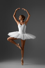 graceful ballerina in white tutu and pointe shoes on gray background - obrazy, fototapety, plakaty