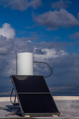Obraz premium solar rooftop boiler on a sunny day against the background of the sky with clouds