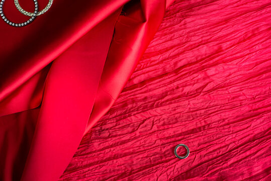 
Red backgrounds from different fabrics. Crumpled taffeta and satin and steel rings. Two rings next to each other and one small one Template for the text of the announcement invitation message.