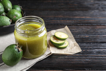 Feijoa jam and fresh fruit on black wooden table. Space for text