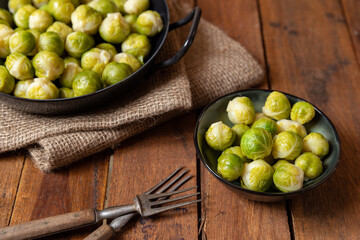 gekochter grüner Rosenkohl in Topf auf einem Tisch aus  braunem Holz in der Küche
