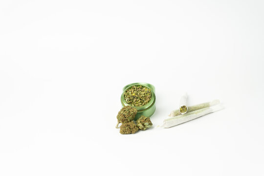 Buds of marijuana, grinder with crushed weed cannabis and rolled joints on white background.Medical and medicine concept.