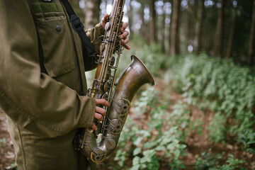 A hand held saxophone in the forest bokeh background