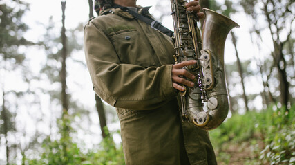 A hand held saxophone in the forest bokeh background