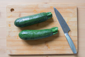Fresh green zucchini on wooden board with knife. Cooking vegetables