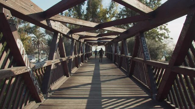 Modern wooden bridge above a highway with people passing