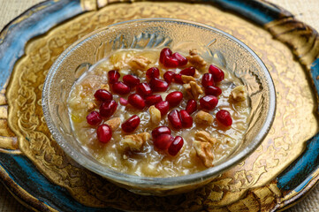 Ashure or Noah's pudding, the turkish dessert porridge in glass bowl on golden dish