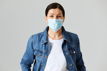 Senior woman wearing a protective face mask isolated on gray background in studio