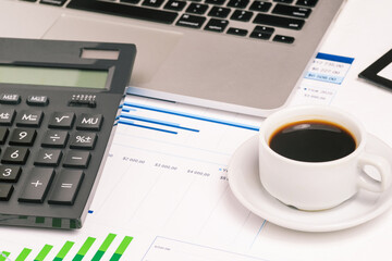 Accounting and analytics. Work desk with a cup of coffee, a computer and diagrams. Budgeting and economics. Tax calculation