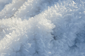Hoarfrost background texture. Fresh ice and snow winter backdrop with snowflakes and mounds. Seasonal wallpaper. Frozen water geometrical shapes and figures. Cold weather atmospheric precipitation.