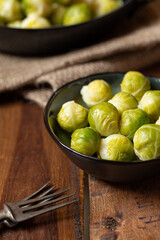 gekochter grüner Rosenkohl in Topf auf einem Tisch aus  braunem Holz in der Küche