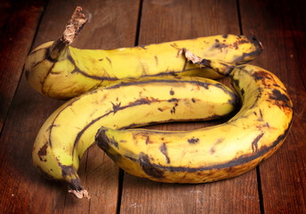 Banane molto mature disposte su tavole di legno.