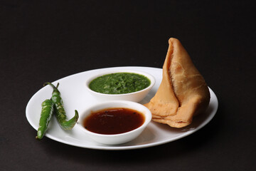Indian snack Homemade spicy and delicious samosa served with green, tamarind chutney.